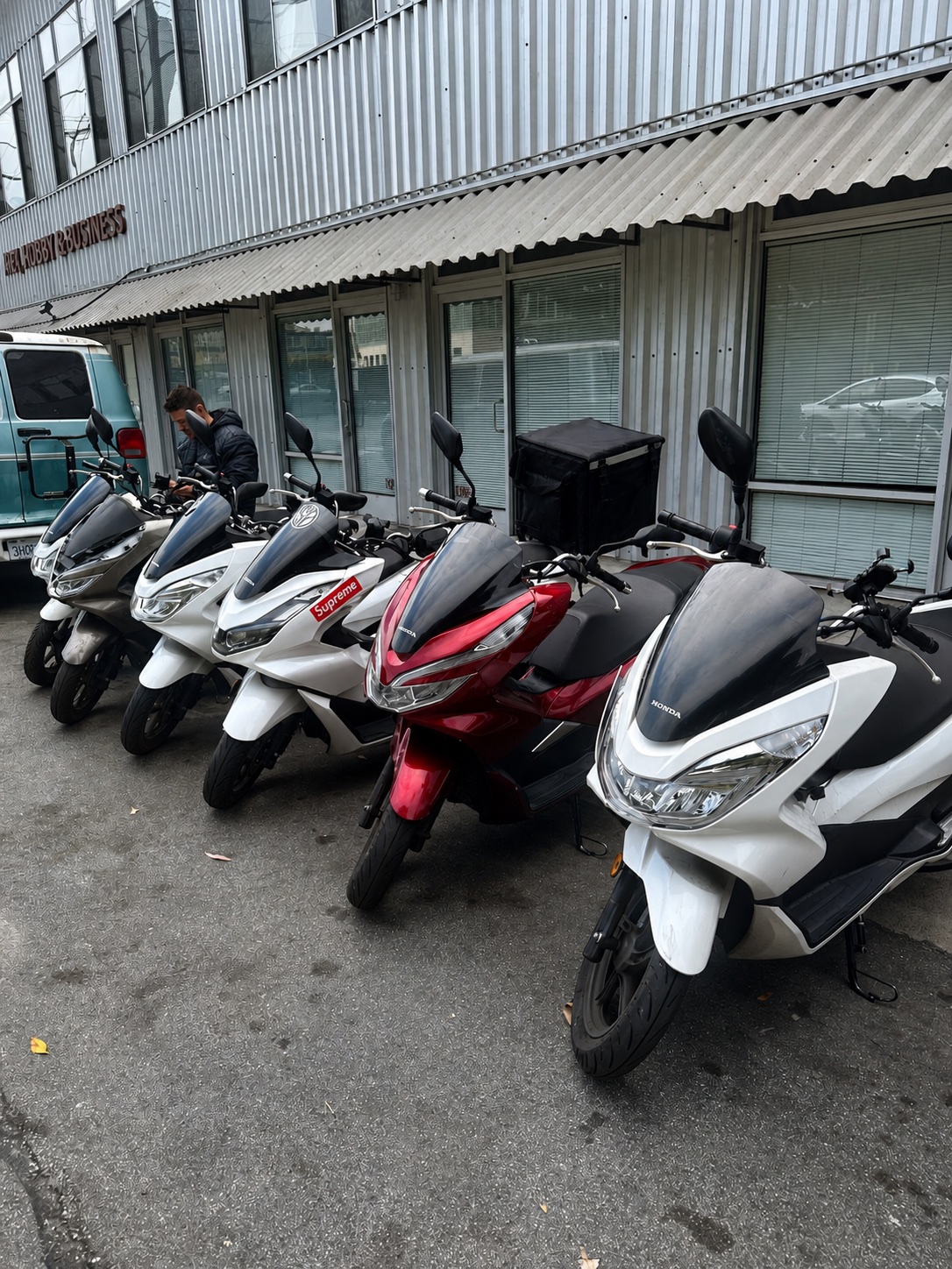Honda PCX scooters lined up beside the Real Facts workshop